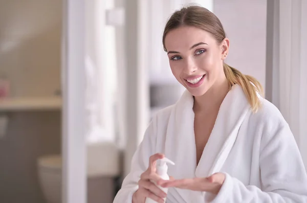 Mulher bonita após o banho aplicando creme corporal na pele um — Fotografia de Stock