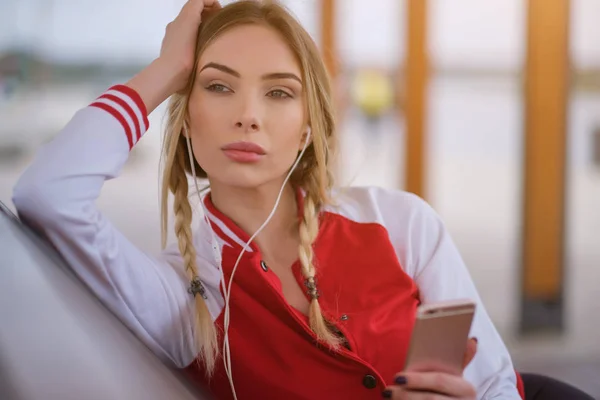 Mujer joven atractiva escuchando música en los auriculares, mirando — Foto de Stock