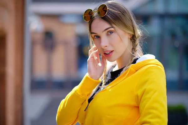 穿着黄色运动衫散步的女孩。 在后台街道上 — 图库照片