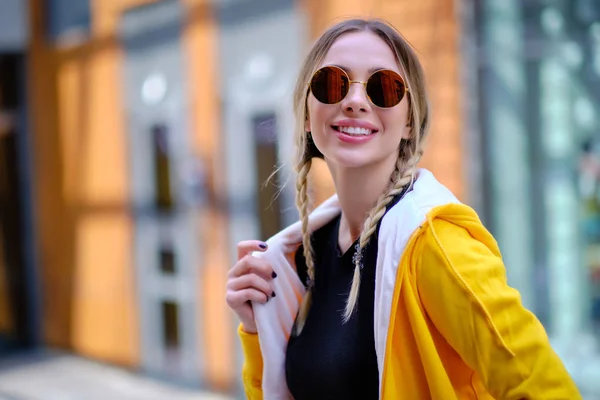 Chica con una sudadera amarilla en un paseo. en las calles de fondo — Foto de Stock