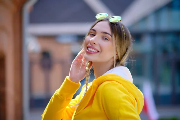 Chica con una sudadera amarilla en un paseo. en las calles de fondo —  Fotos de Stock