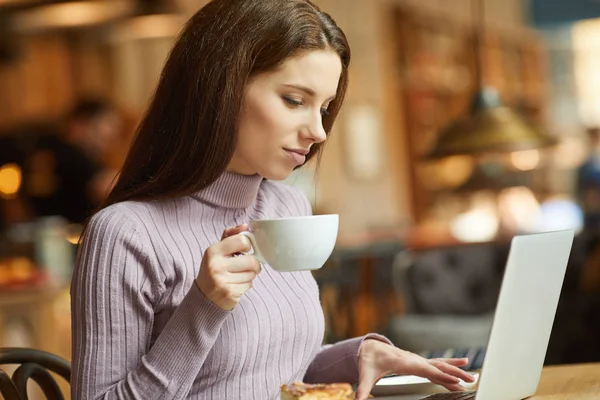 Mooie jonge vrouw met een kopje thee in een café — Stockfoto