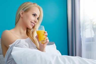 Yatağında meyve suyu olan genç ve güzel bir kadın.