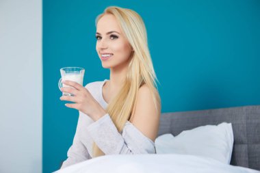 Yatağında meyve suyu olan genç ve güzel bir kadın.