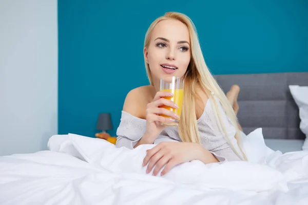 Giovane bella donna con tazza di succo a letto — Foto Stock