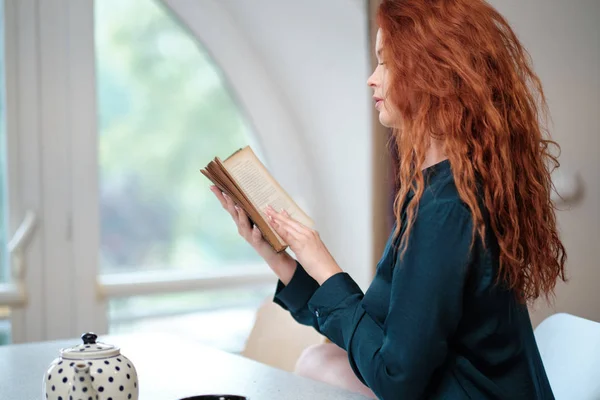 Kahve ile kitap okuyan kızıl saçlı kadın. — Stok fotoğraf