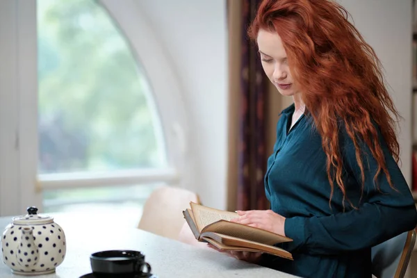 Kahve ile kitap okuyan kızıl saçlı kadın. — Stok fotoğraf