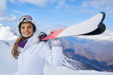 Maske takan ve elinde tutan güzel kayakçı kız portresi.
