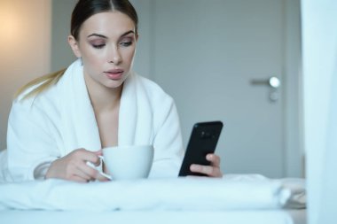 Yataktaki kız. O, akıllı telefona bakar. Soci 'nin etkisi