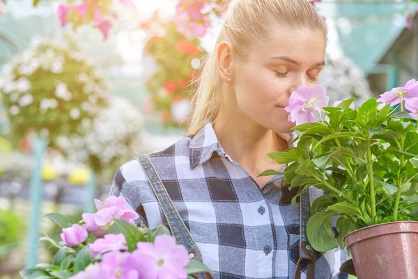 Mujer joven jardinería en invernadero.Ella seleccionando flores . — Foto de Stock