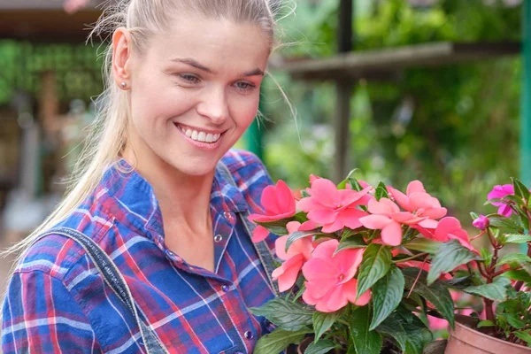 Mujer joven jardinería en invernadero.Ella seleccionando flores . — Foto de Stock