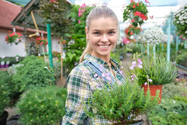 Mujer feliz jardinero elegir maceta con anturios en gar — Foto de Stock