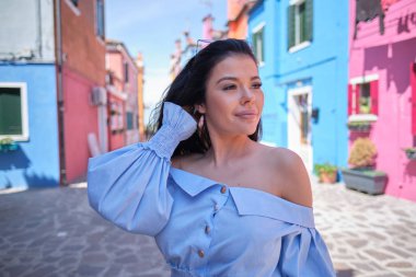 traveler woman posing among colorful houses on Burano island, Ve