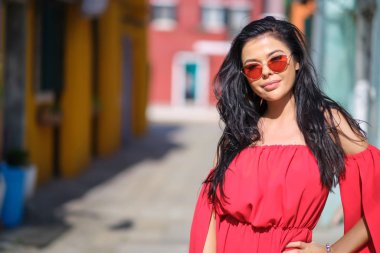 traveler woman posing among colorful houses on Burano island, Ve