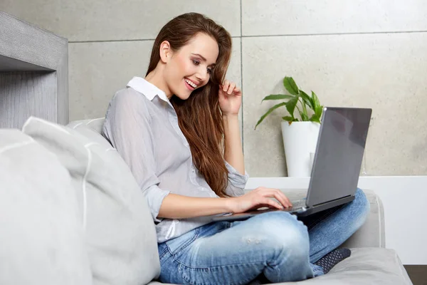 Γυναίκα που χρησιμοποιεί ένα φορητό υπολογιστή ενώ χαλαρώνει στον καναπέ — Φωτογραφία Αρχείου