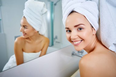 Genç ve sağlıklı bir kadının yüzü ve aynadaki yansıması.