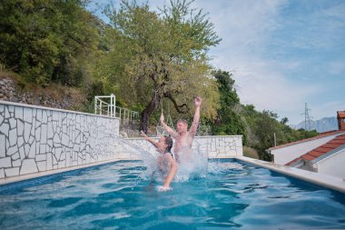 Neşeli genç adam ve bayan yüzme havuzunda dinleniyorlar. Sudaki çift.