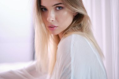  Neşeli, sarışın, sıradan giyinmiş, kameraya bakarak mutlu olan bir kadın. Güzel bir kadının ev fotoğrafı.