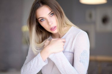  Neşeli, sarışın, sıradan giyinmiş, kameraya bakarak mutlu olan bir kadın. Güzel bir kadının ev fotoğrafı.