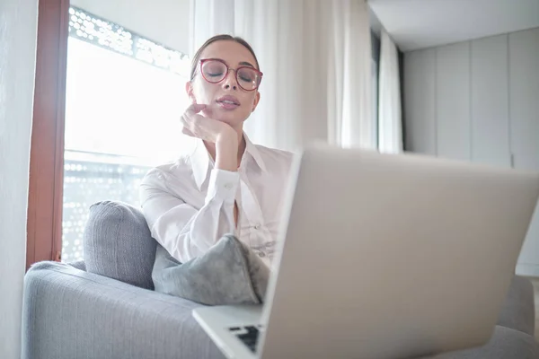 Frau Mit Brille Sitzt Mit Computer Auf Couch Schaut Nach — Stockfoto