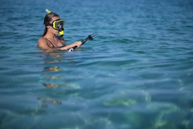 Bikinili bir kadın yaylı tüfekle avlanır.