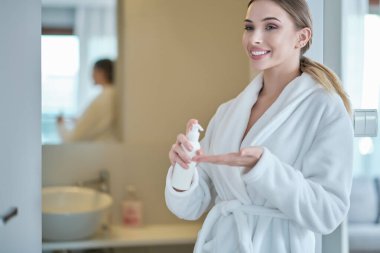 El temizliği. Bornozlu kadın ellerini dezenfekte eder. virüs koruması