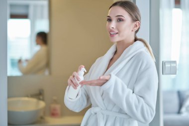 El temizliği. Bornozlu kadın ellerini dezenfekte eder. virüs koruması