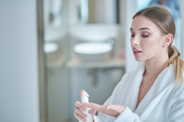 El temizliği. Bornozlu kadın ellerini dezenfekte eder. virüs koruması