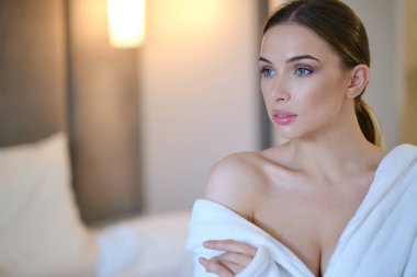 Evde bornozlu bir kadın dinleniyor.