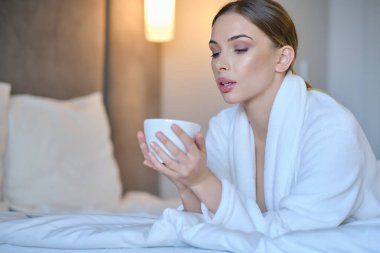 Evde bornozlu bir kadın dinleniyor.