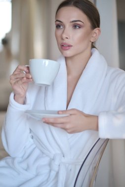 Evde bornozlu bir kadın dinleniyor.