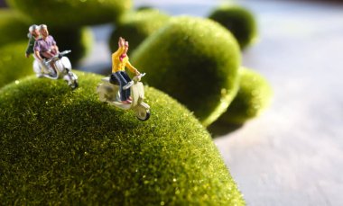 Bir grup gezgin minyatür insan figürleri motosiklet sürüyor, yeşil kavram.