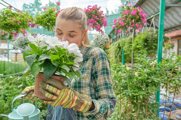 Nice positive flower seller holding  water can and watering flowers while being involved in work