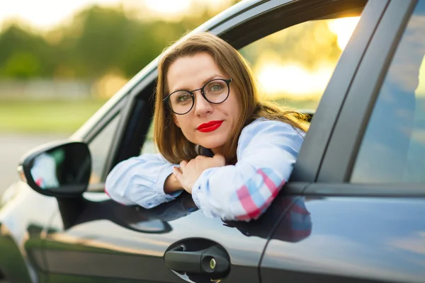 Νεαρή γυναίκα ευτυχισμένη που κάθεται σε ένα αυτοκίνητο — Φωτογραφία Αρχείου