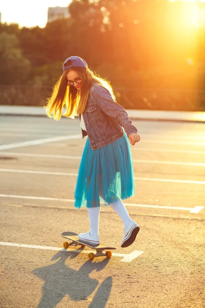 Schöne junge Frau mit Skateboard, bei Sonnenuntergang beleuchtet — Stockfoto