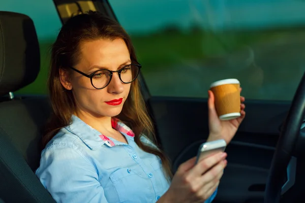 Empresaria que envía un mensaje de texto y beber café mientras d — Foto de Stock