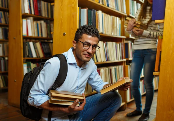 Junges Studentenpaar sucht sich Bücher in der Bibliothek aus — Stockfoto
