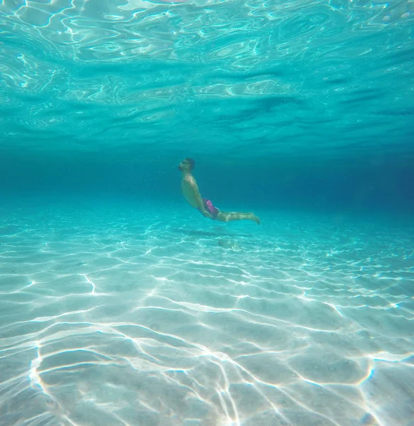 Человек в очках ныряет в голубую чистую воду моря — стоковое фото