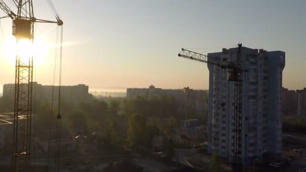 Industriële bouwkranen en silhouetten boven de zon bij zonsopgang — Stockvideo