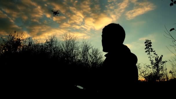 Man beheert drone. Silhouet tegen het avondrood — Stockvideo