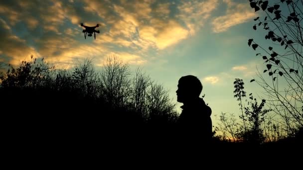 Mann steuert Drohne. Silhouette vor dem Sonnenuntergang — Stockvideo