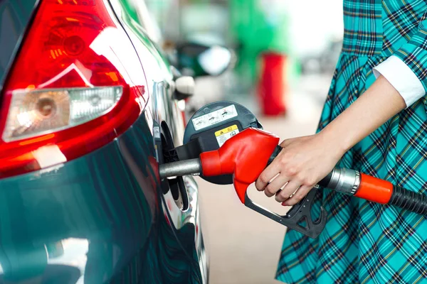 Mujer llena gasolina en el coche en una gasolinera — Foto de Stock