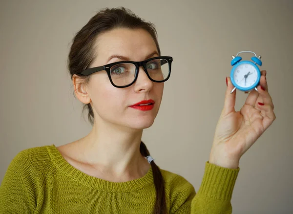 생각에 잠겨있는 젊은 여자의 손에서 작은 파란색 알람 시계 — 스톡 사진