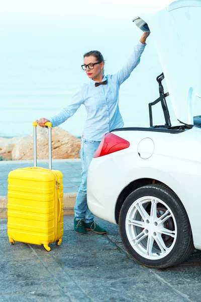 Woman loading luggage into the back of convertible car — Stock Photo, Image