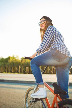 Şehir arka plan üzerinde bir bisiklet sürme şapkalı güzel bayanı 