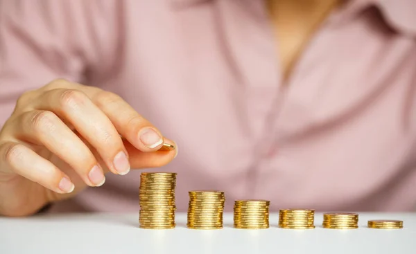 Mano femenina apilando monedas de oro en columnas crecientes — Foto de Stock