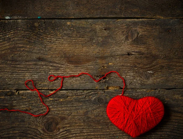 Red heart shape made from wool on old shabby wooden background — Stock Photo, Image