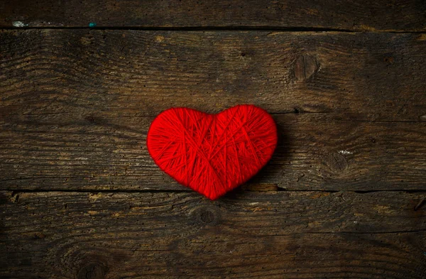 Yün eski püskü ahşap arka plan üzerinde yapılan kırmızı kalp şekli — Stok fotoğraf