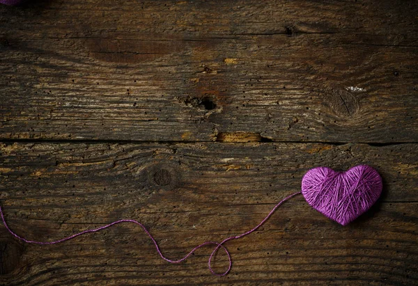 Purple Heart with a ball of thread on on old shabby wooden backg