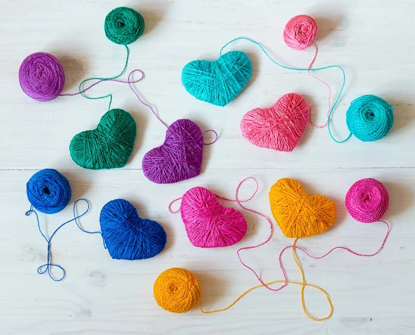 Veelkleurige hart met een ballen van wol op witte houten achtergrond — Stockfoto